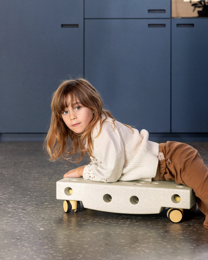 Toddler riding on MODU Scooter Board built from Curiosity Set in Sand Grey Honey Yellow.