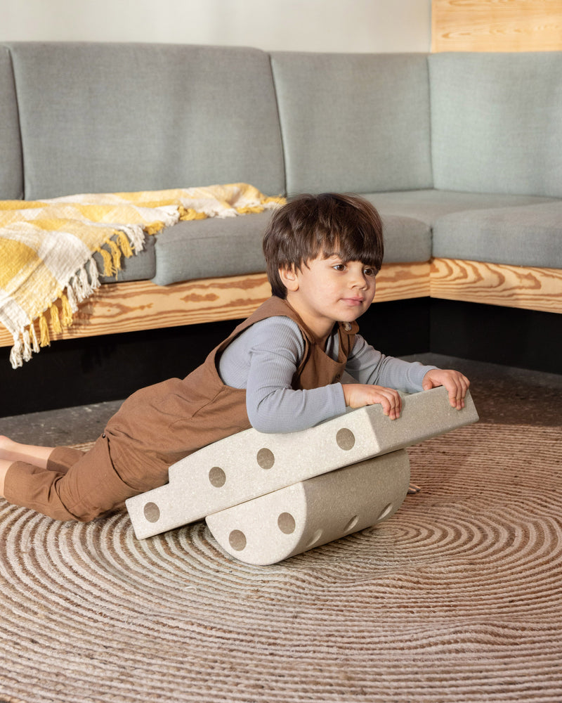 Toddler playing in living room on balance board built from Curiosity Set in Sand Grey Honey Yellow.