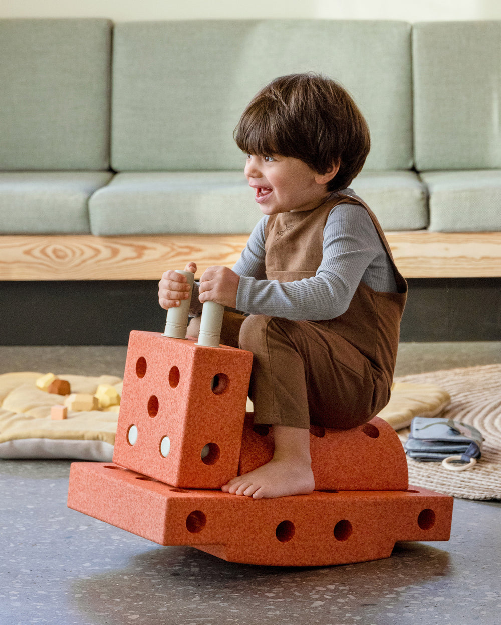 Young toddler having fun riding MODU rocker, practicing balance skills. Built from Explorer Set in Burnt Orange Dusty Green.