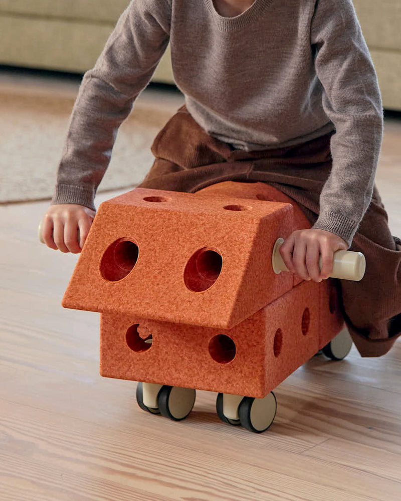 Toddler riding on MODU swirly ride, a fun ride-on for toddlers and kids, built from Explorer Set in Burnt Orange Dusty Green.