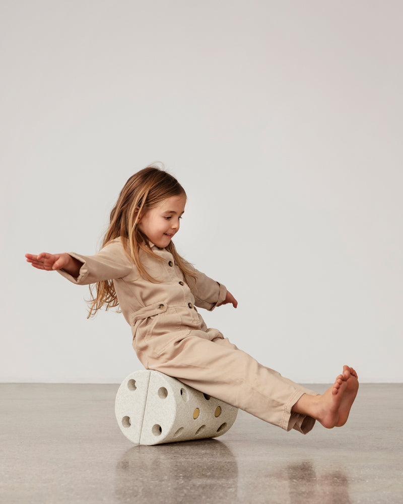 Toddler sitting on MODU Roller in Sand Grey Honey Yellow, practicing balance.