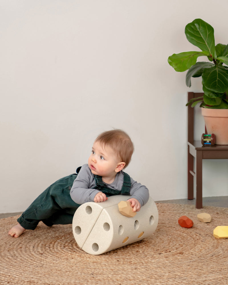Baby doing tummy time using MODU Roller in Sand Grey Honey Yellow.
