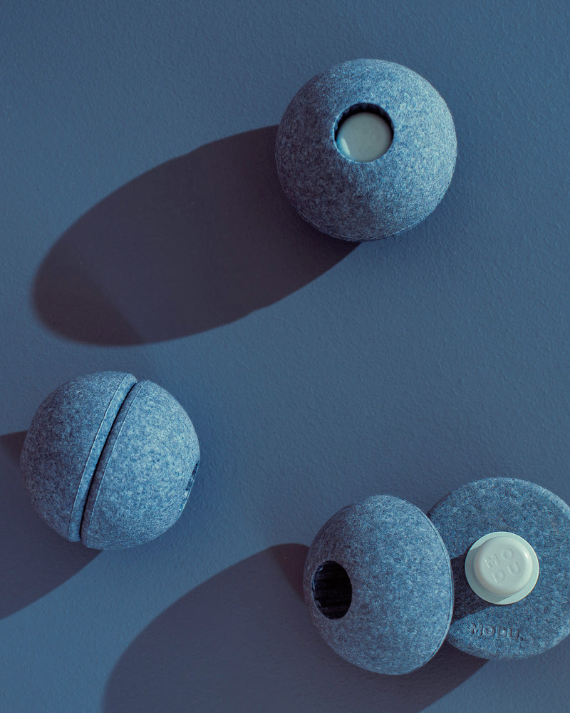 Deep blue MODU Foam Balls shown fully assembled and split into half-spheres, demonstrating the toy's open-ended functionalities.