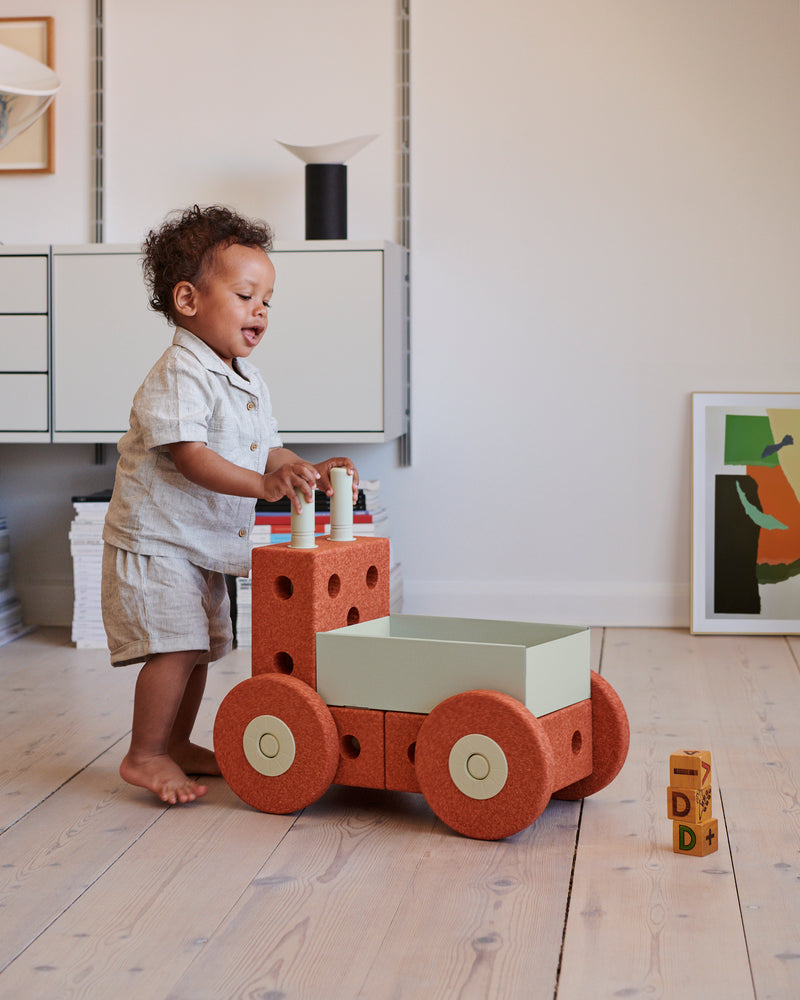A child pushes a MODU 3-in- 1 Baby Walker across a wooden floor.