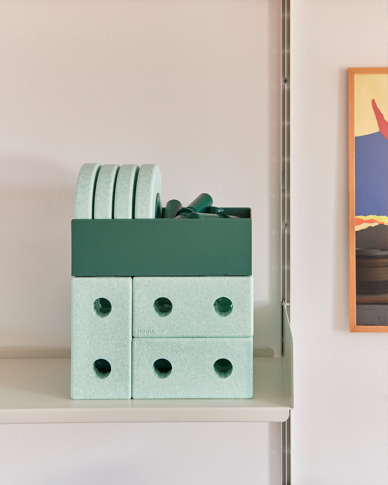 Components of the MODU 3-in-1 Baby Walker in ocean mint and forest green stored neatly on a shelf.