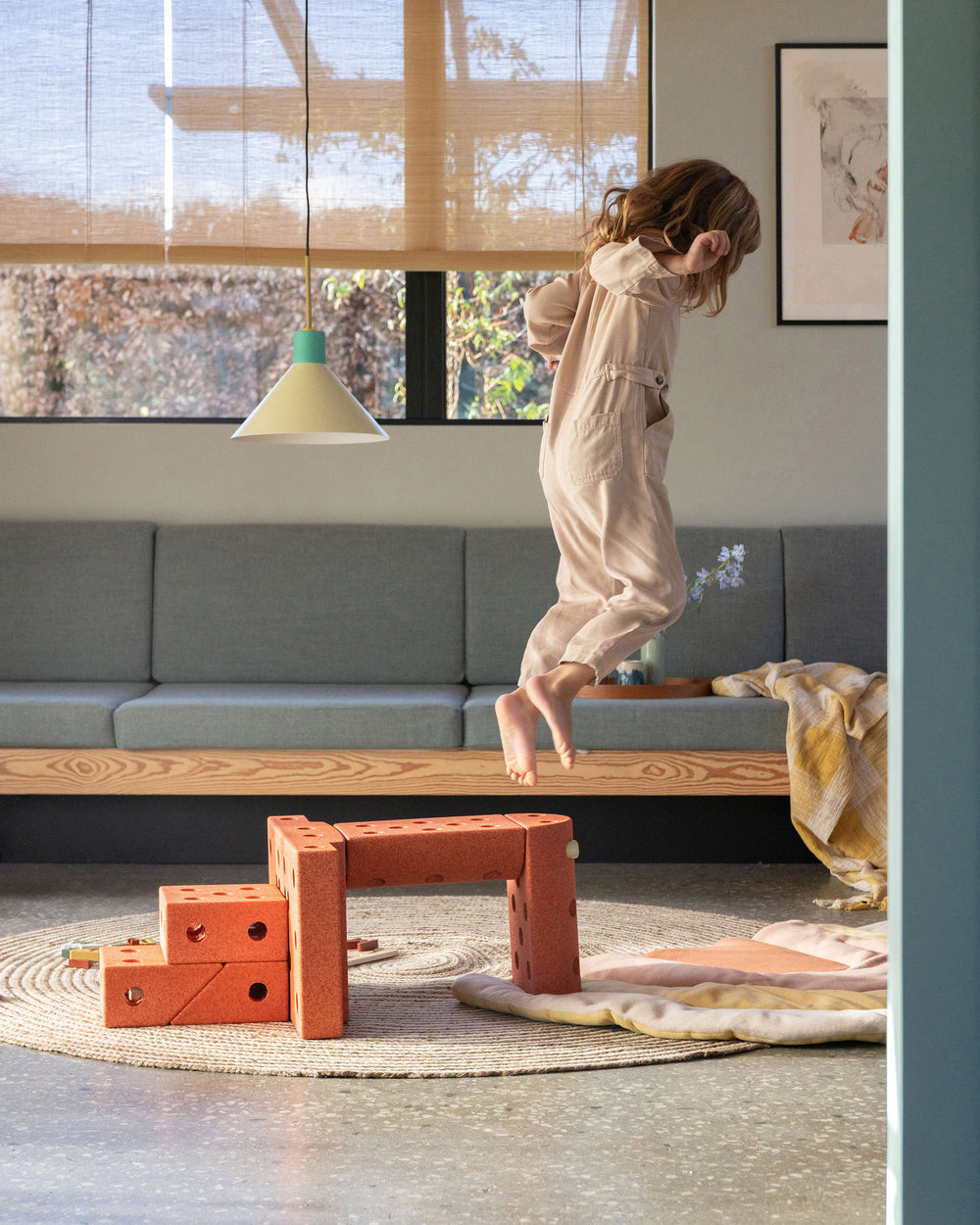 Toddler playing in the living room, jumping off MODU jump tower built from Dreamer Set in Burnt Orange Dusty Green.
