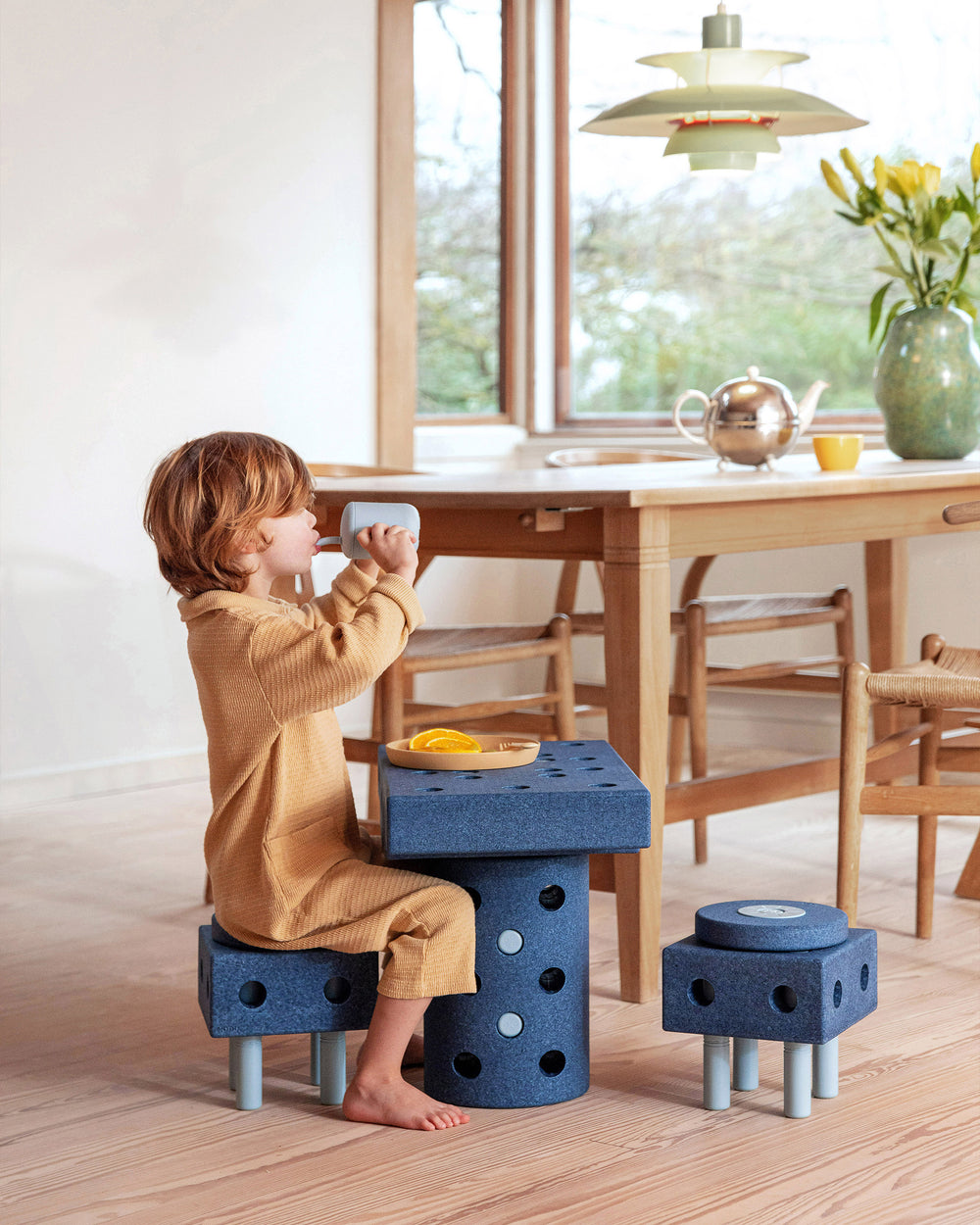 Toddler sitting and enjoying breakfast at a MODU stool and table set built from Dreamer Set in the colour Deep Blue Sky Blue.