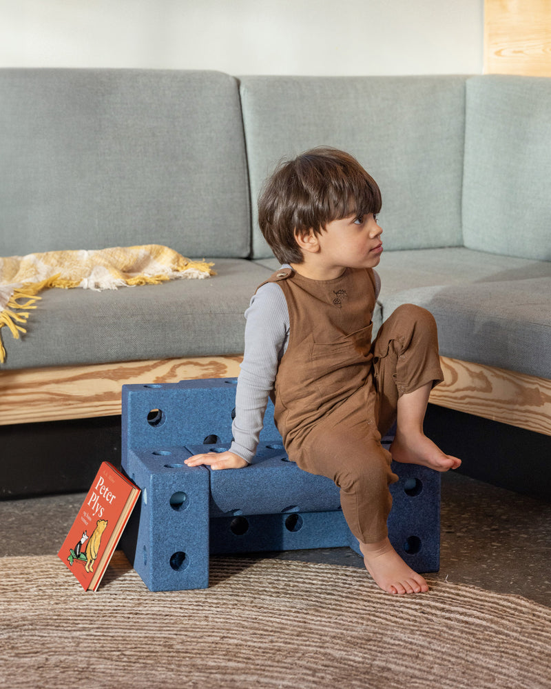 A child sits on a small toddler bench built from the MODU Explorer Set in living room.