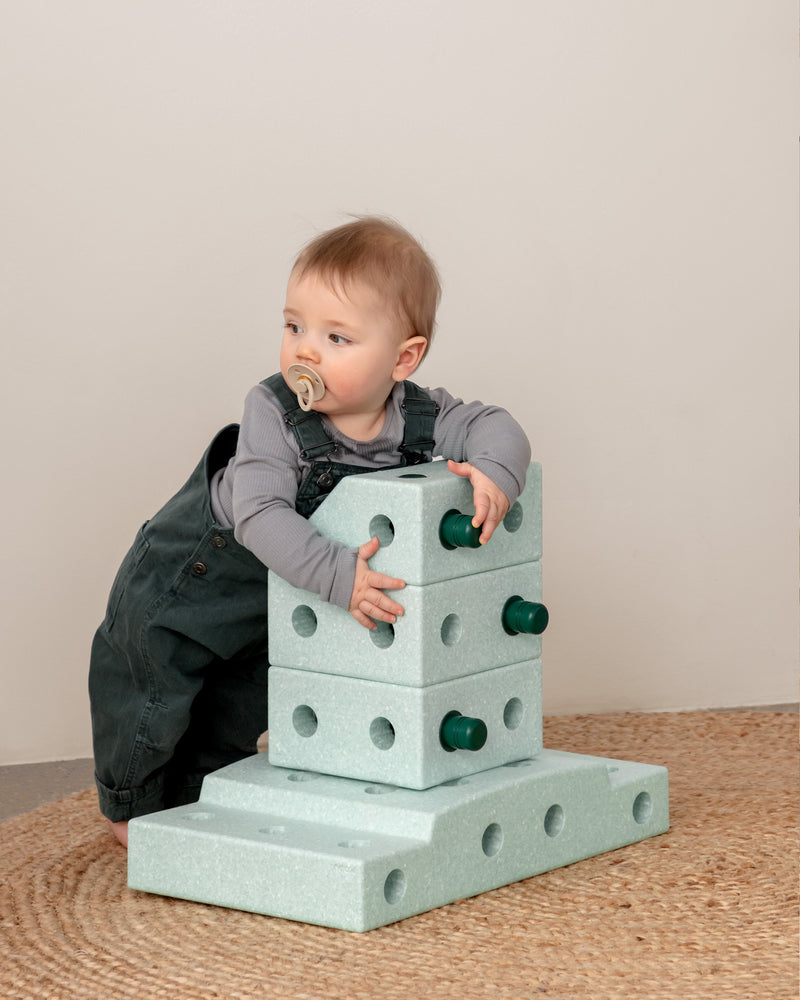 Baby practicing standing with MODU stand-up tower, built from Explorer Set in the colour Ocean Mint Forest Green.