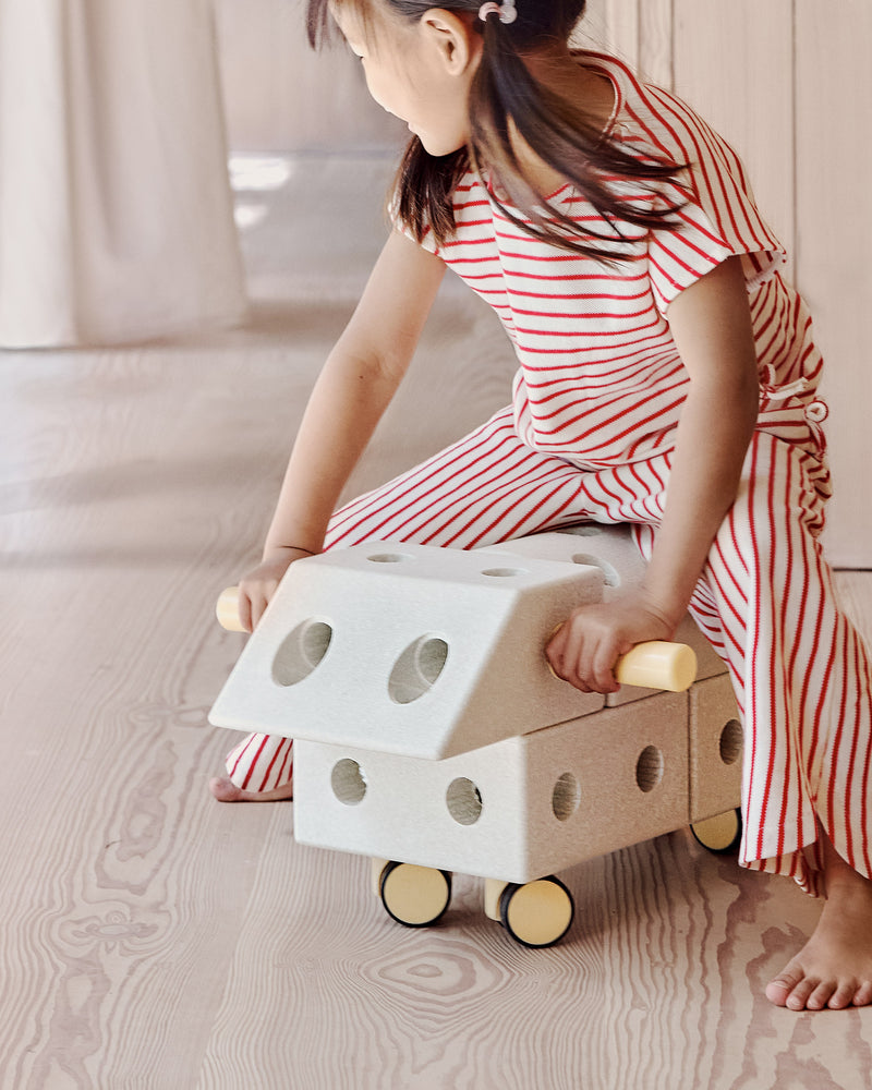 A child plays indoors riding a fast ride-on toy built from the MODU Explorer Set.