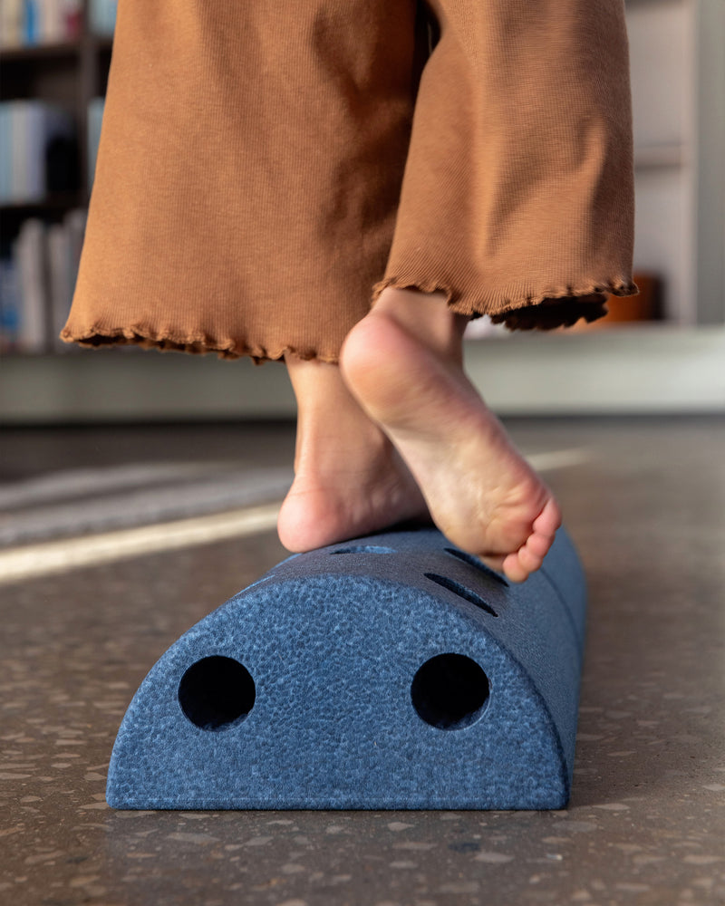 A child walks barefoot across an indoor obstacle built from deep blue MODU Kids' Stool.