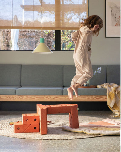 Kleinkinder springen vom MODU-Sprungturm, einem lustigen Aktivitätsspielzeug zur Entwicklung motorischer Fähigkeiten. Gebaut aus Dreamer-Set.