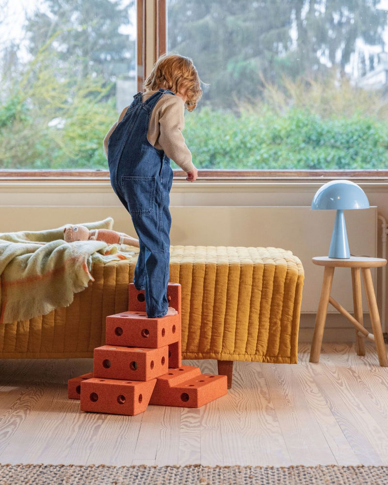 Toddler climbing on MODU stairway to get into bed in kids room. Product color: Burnt Orange Dusty Green.