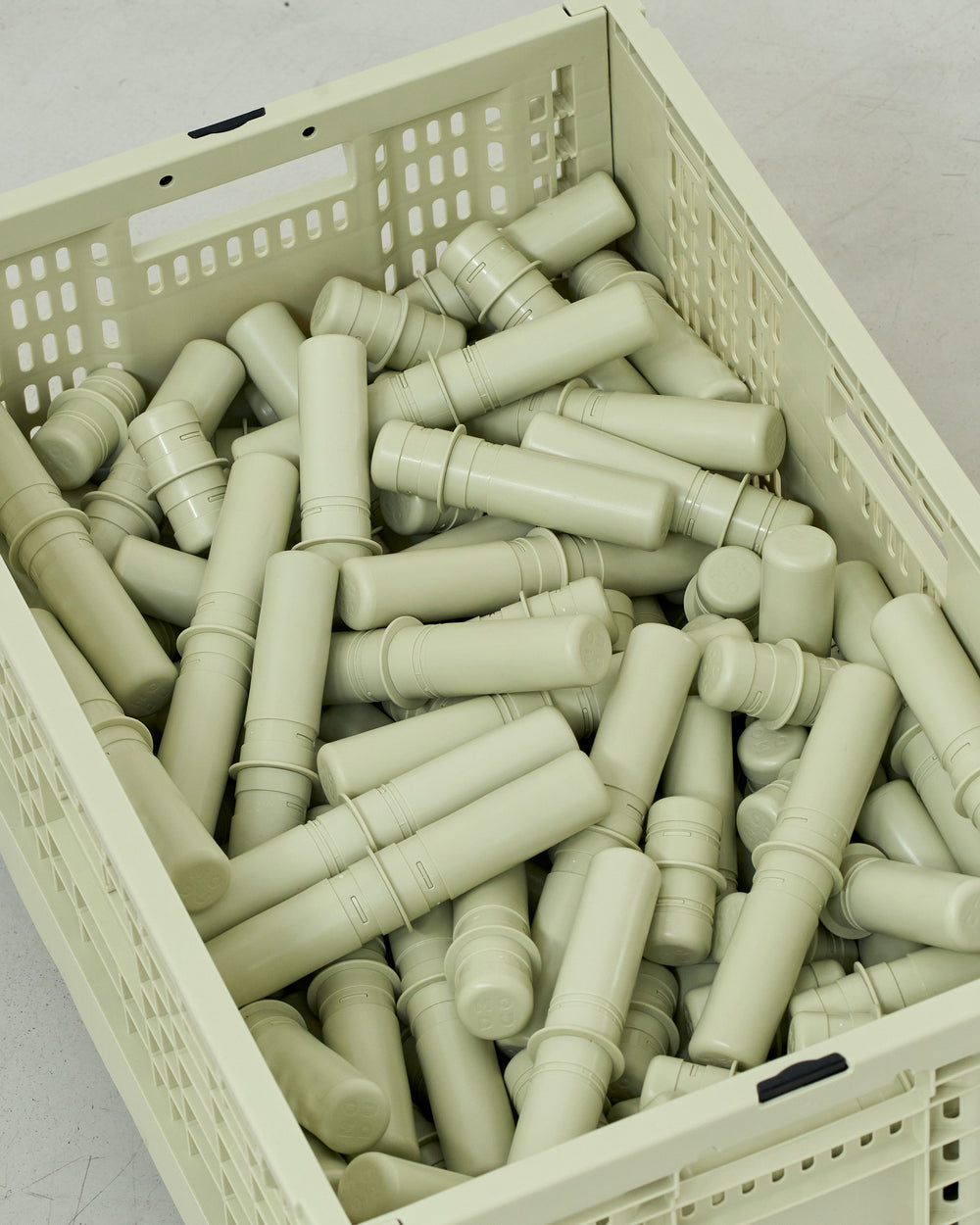 Dusty green MODU pegs in a dusty green crate on a light gray background