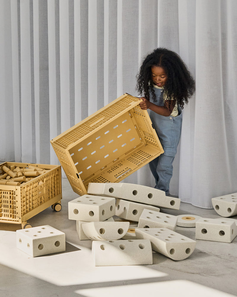 Barn leger med MODU byggeklodser og kasser i minimalistiske omgivelser