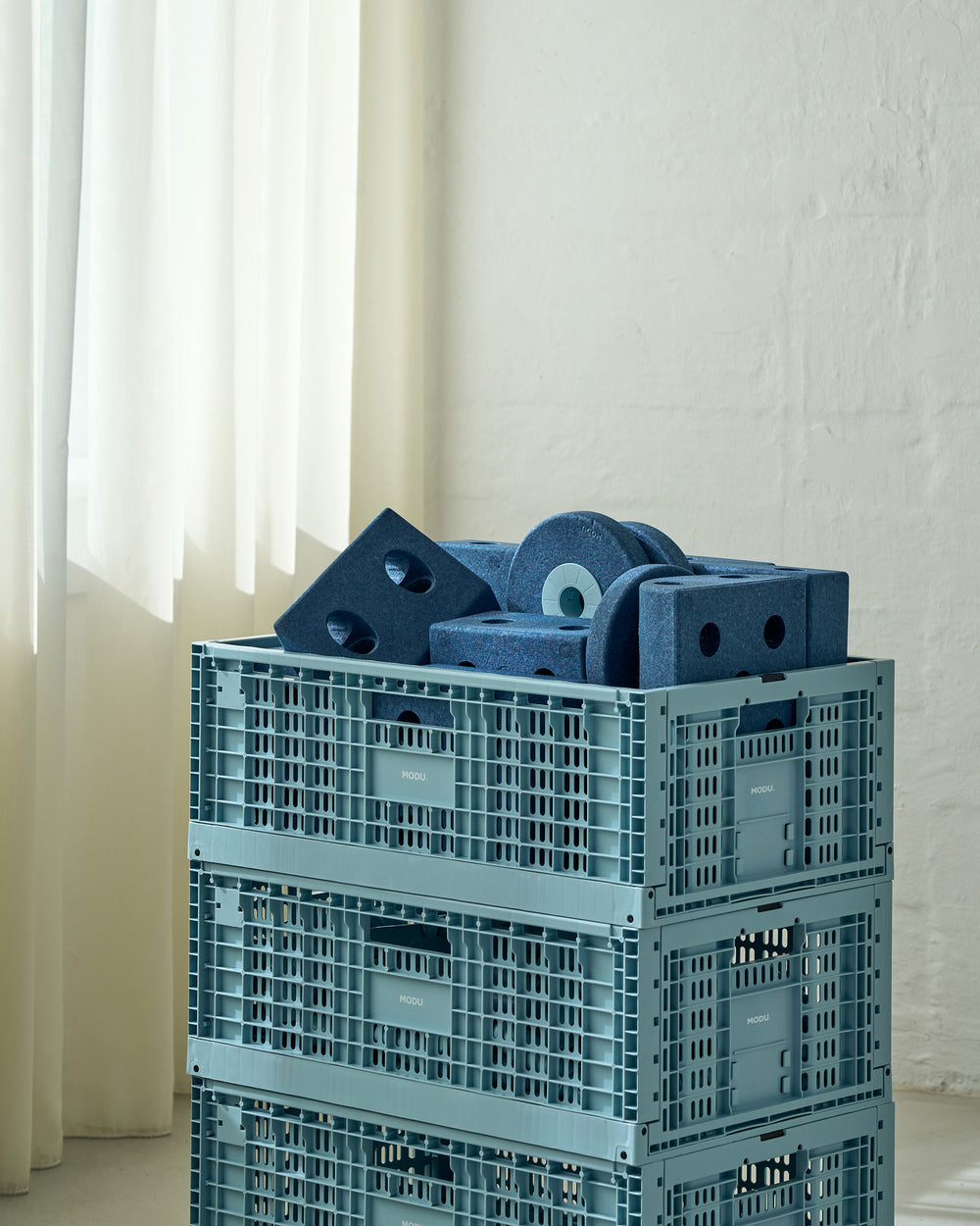 Stack of blue plastic crates with blue foam blocks on a light background