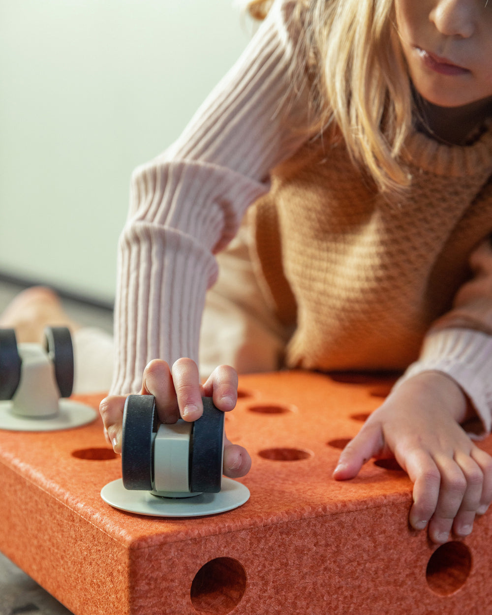 Toddler building ride-on using MODU swirly wheel in Dusty Green.