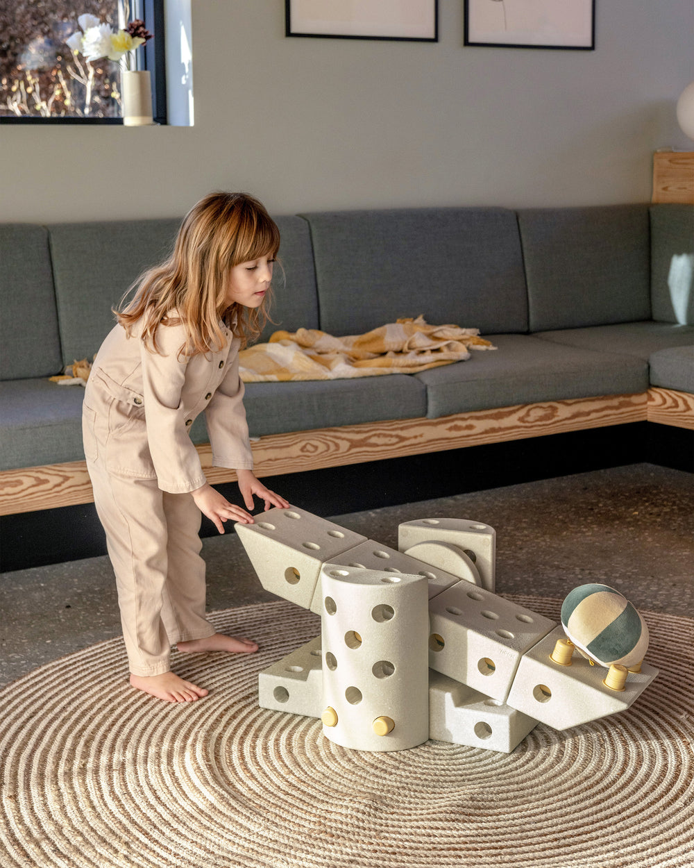 Child playing in the livingroom with MODU Catapult built from a Dreamer Set in the colour Sand Grey Honey Yellow.
