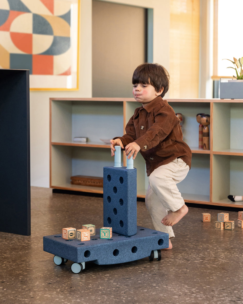 Toddler pushing MODU wheely cart around the living room. Built from Explorer Set in the colour Deep Blue Sky Blue.